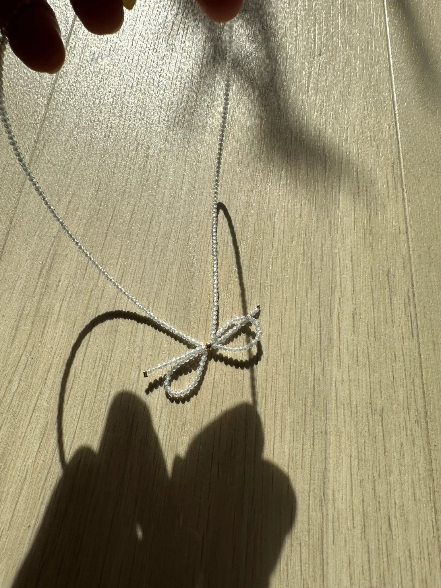 Sløjfe halskæde i 18K forgyldt kirurgisk stål med hvide krystalsten